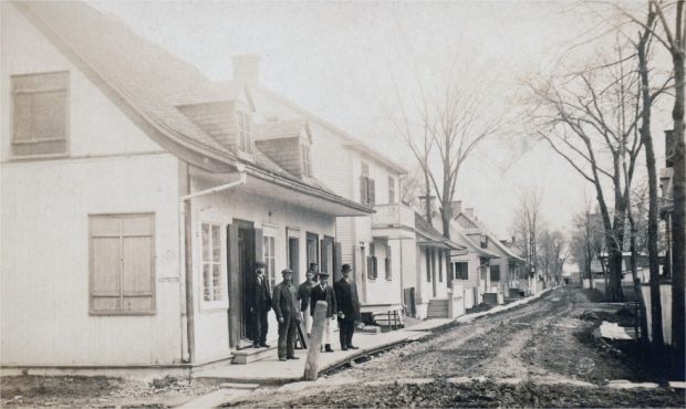 A dirt road with ancestral homes and men