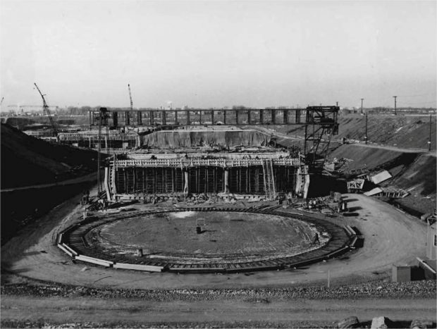 A concrete structure under construction in a trench and a bridge crane