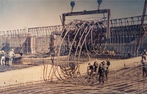 Workers unwinding spools of steel cable in a structure