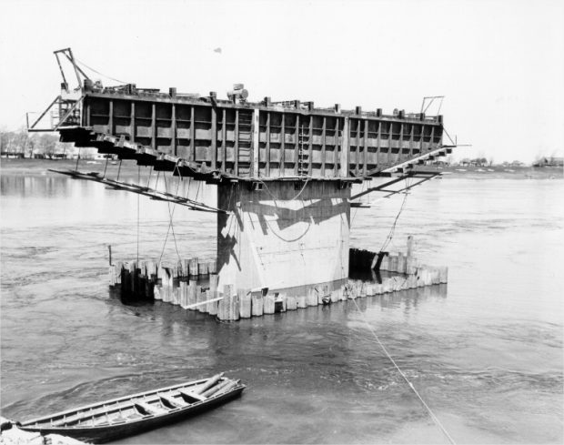 A bridge pillar under construction with a rowboat in the foreground