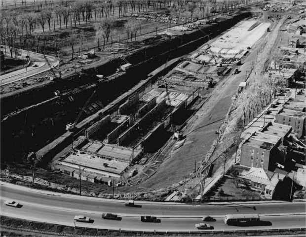 A structure under construction with buildings and cars on a street