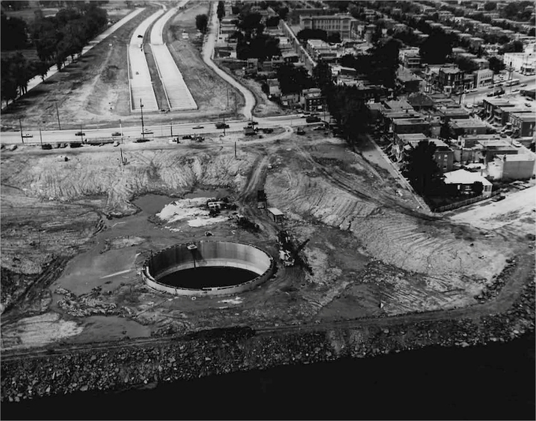 A highway under construction with a gaping hole near a city and a river