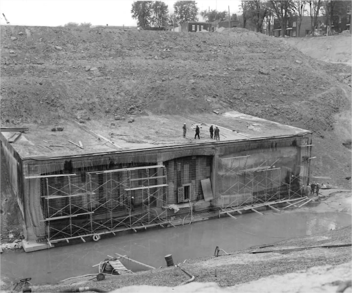 Men in a structure under construction with residential buildings in the background