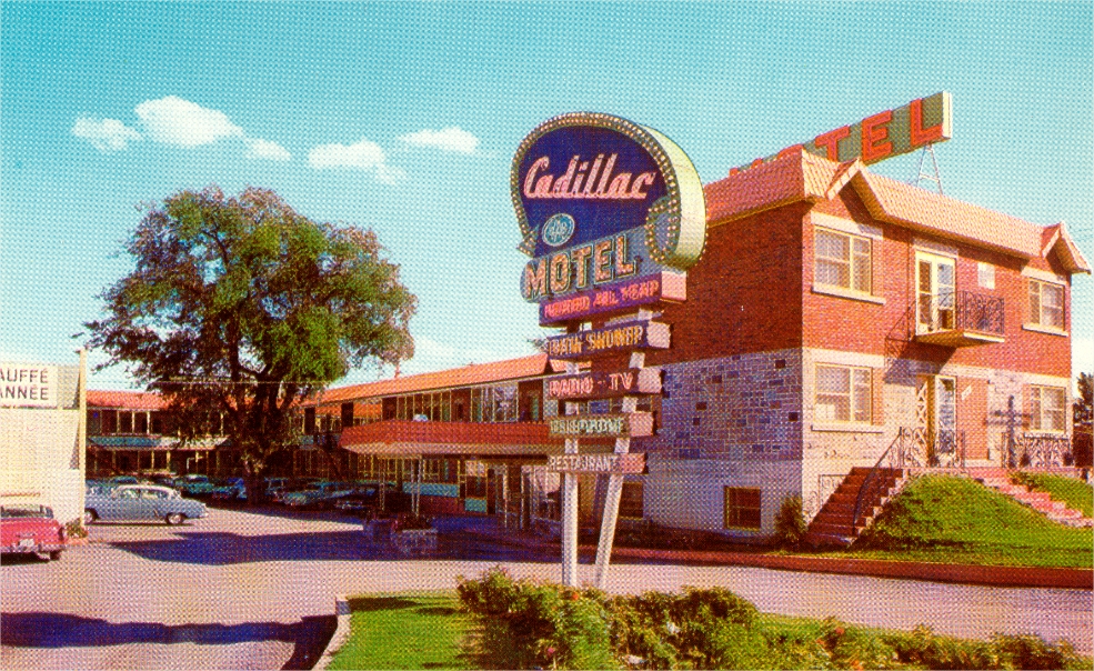 A motel with a poster from the 1950s and parked cars