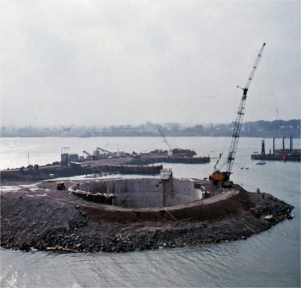 A crane on a concrete structure surrounded by earth and water