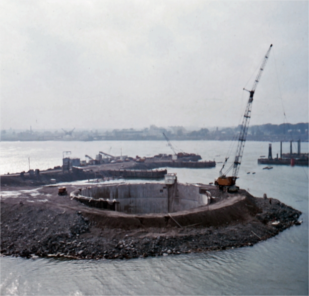 A crane on a concrete structure surrounded by earth and water