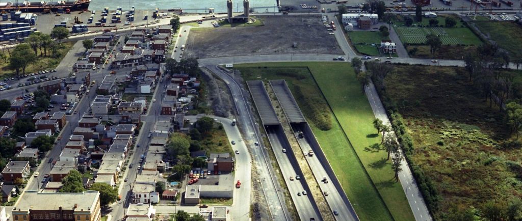 Cars on a highway with a port and a river in the background