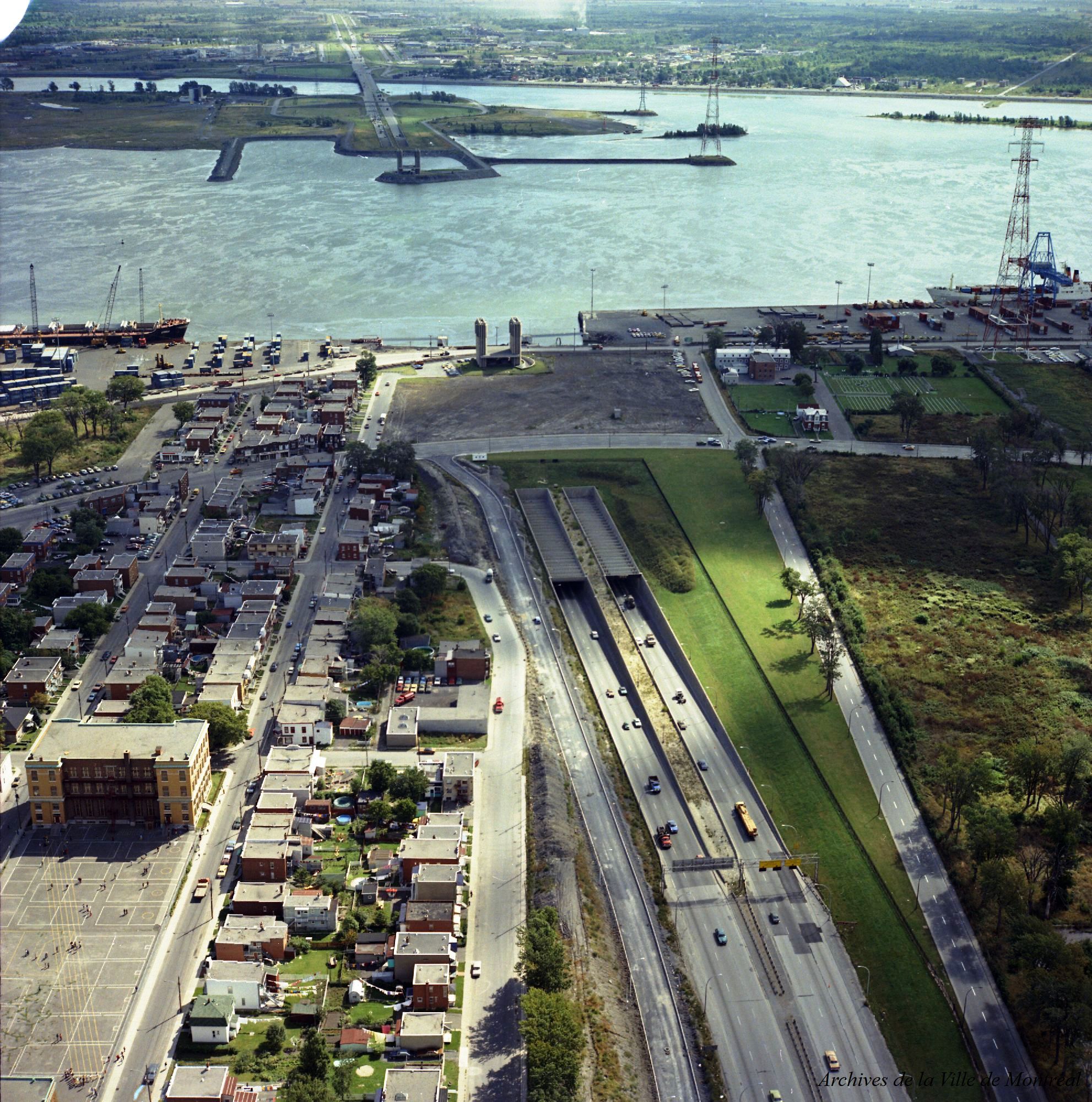 Cars on a highway with a port and a river in the background