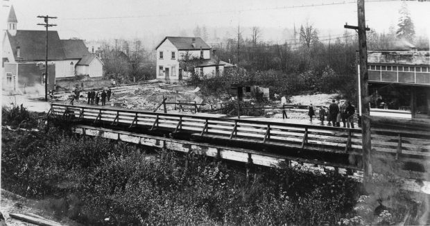 A small crowd gathering on two sides of a damaged bridge
