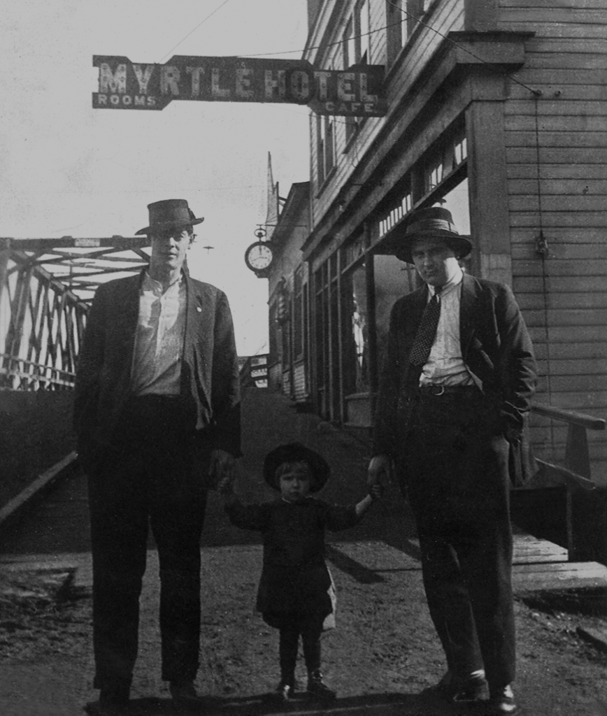 Two men and a child pose in front of the Myrtle hotel