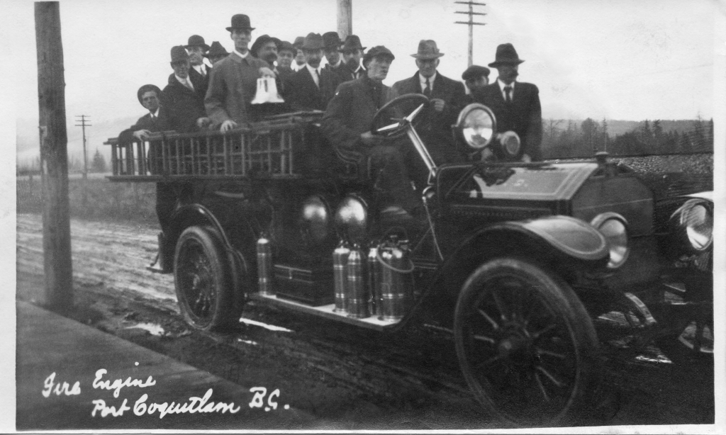 A large group of men in suits stand in a fire engine facing the camera