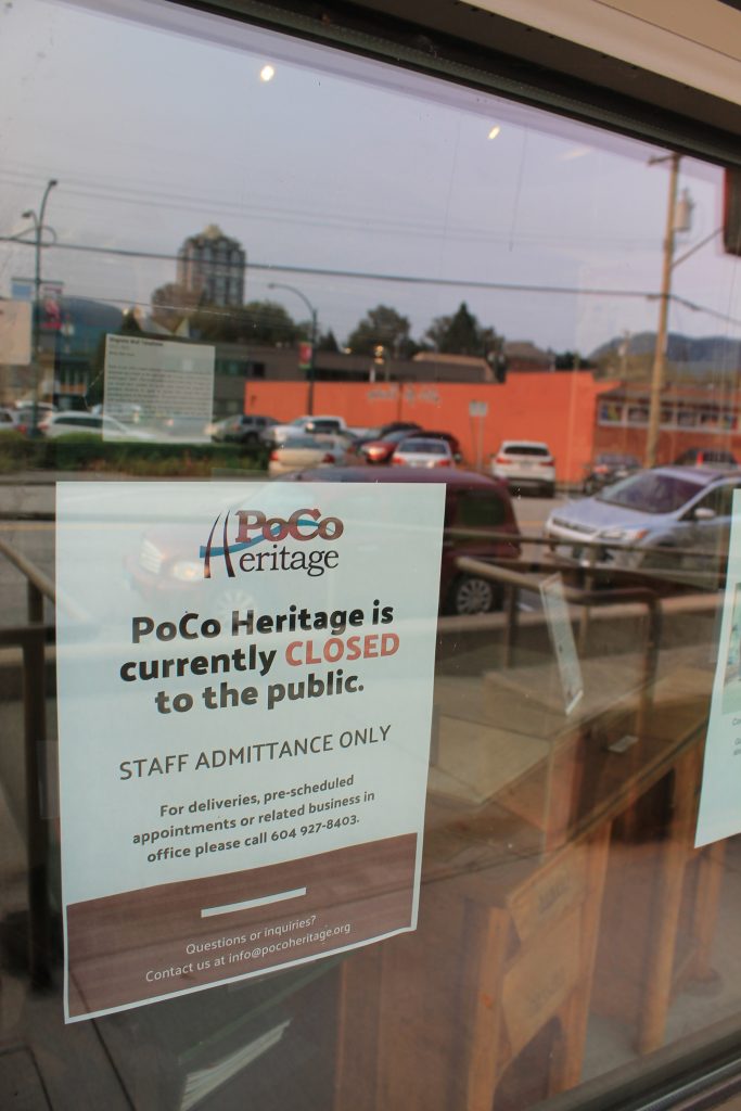 Un panneau fermé avec le logo du PoCo Heritage et un texte collés à une fenêtre.