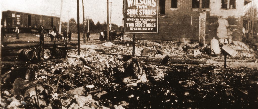 Ruins of a burnt building with a damaged stone structure in the background