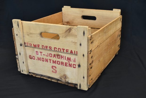 Colour photo of a wooden crate with the name “Ferme des coteaux St-Joachim Co. Montmorency S” stamped on the end facing the camera.