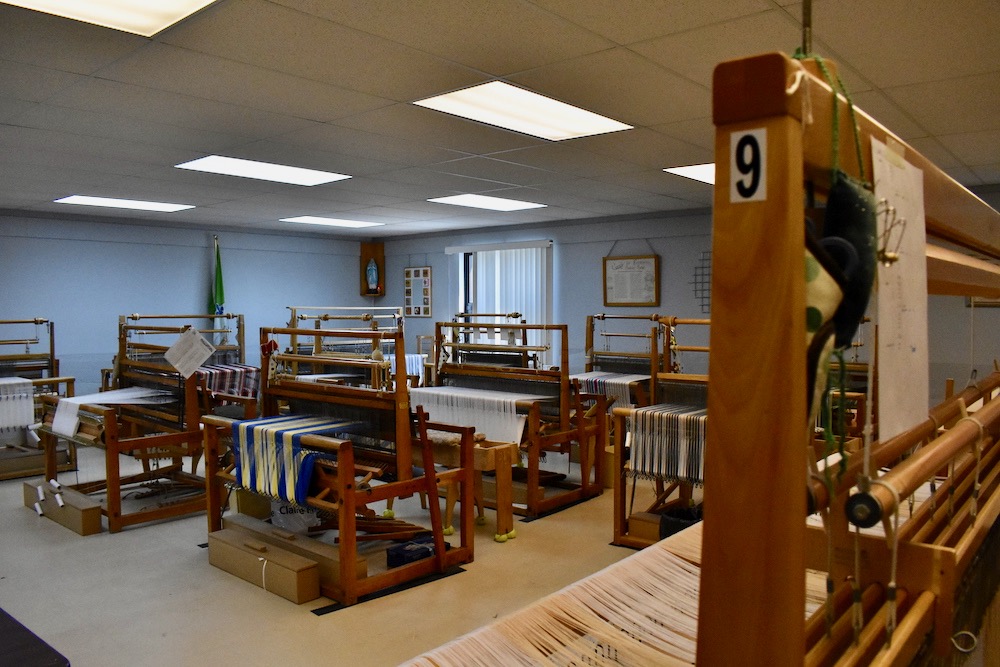 Colour photo of a room with more than ten large looms.