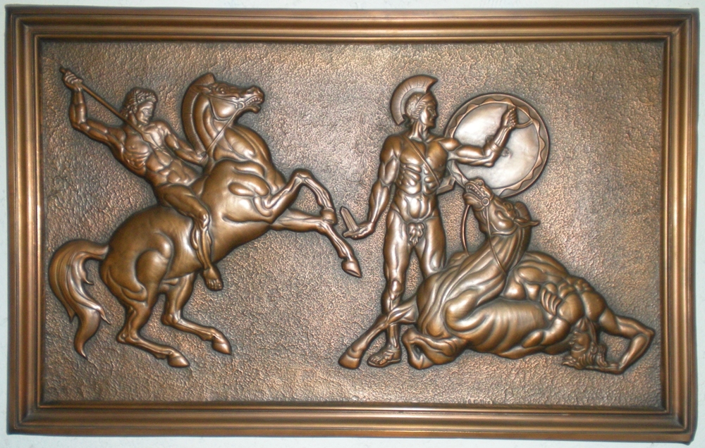 Colour photo of an embossed copper work of art depicting a warrior on horseback wielding a lance as he is poised to attack a helmeted man holding a shield and sword. A third figure is draped over the body of a wounded horse.