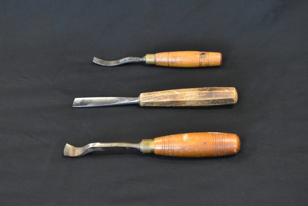 Colour photo showing three wood-handled gouges with different shaped blades against a black background.