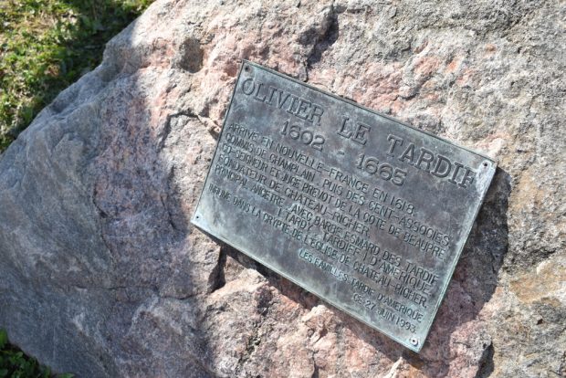 Colour photograph of a commemorative bronze plaque set into a rock that reads (translation): Olivier Le Tardif 1602-1665. Arrived in New France in 1618. Clerk of Champlain, then of Compagnie des Cent-Associés. Co-seigneur and provost-judge of Côte de Beaupré. Founder of Château-Richer. Primary ancestor, together with Barbe Esmard, of the Tardif (Tardy, Tardiff) family of North America. Interred in the crypt of the Château-Richer Church. The Tardif families of North America, June 27, 1993.