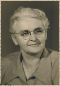 Black and white archival portrait photo of Rose Lachance. Her grey hair is done up in a bun, and she is wearing oval-shaped eyeglasses.