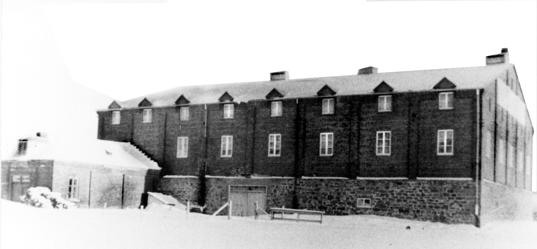 Black and white archival photo showing the A. Toussaint & Cie winery, a large, two-storey brick building. The façade features two rows of eight windows.