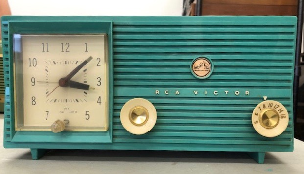 Clock radio made by RCA Victor, Model C419 in 1959. Short, rectangular, made primarily of green plastic. Clock on left, dial on right.