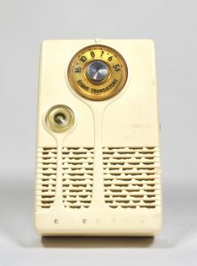 The off-white plastic radio is small and vertically oriented with a dial at the top.
