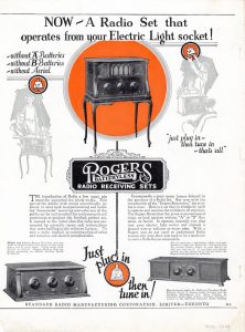 The ad in black, white and red shows a man and women listening to a radio in the top half to the left . On the right, a man beside a radio reaches up to plug the wire into a light socket. In the middle of the page, a receiving set figures more prominently. At the bottom of the page, two more radios are shown under some text.