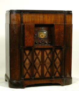 Wooden floor model radio. The speaker below the radio dials is decorated with a diagonal geometric pattern.