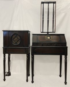 A large detached speaker on four legs and a matching receiver with an antenna-stand centered on top to rotate by hand for better reception. Made of wood.