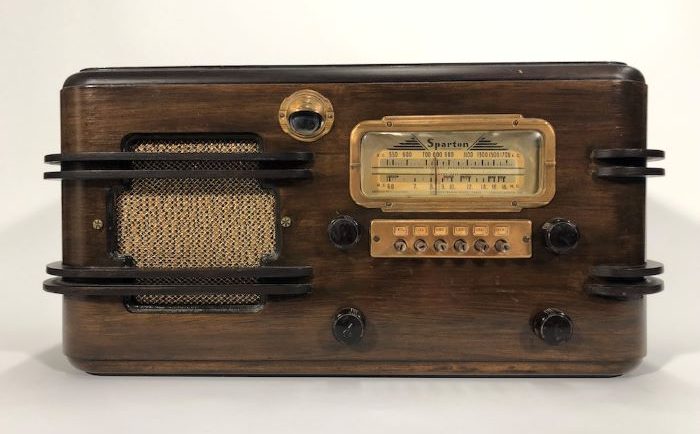 Wooden Sparton radio with four dials, a console, and a speaker on the side, all with brass detailing.