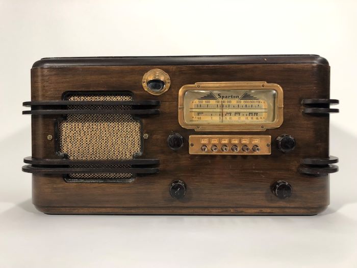 Wooden Sparton radio with four dials, a console, and a speaker on the side, all with brass detailing.