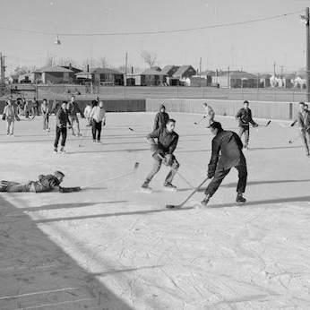 Black and white snapshot of kids playing hockey outdoors in Toronto around 1950.