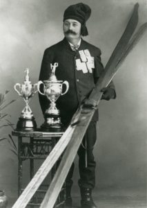 Olaus Jeldness avec une paire de ski et deux trophées de ski. 