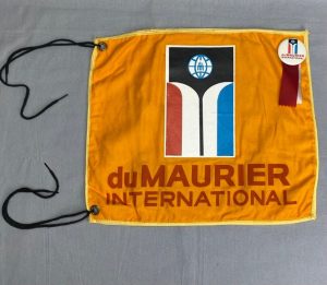 Banderole de porte orange de la Coupe du monde du Maurier International de 1968 avec un bouton souvenir fixé dessus.