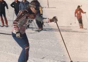Young skier passing in front of four other skiers on a snowy mountain.