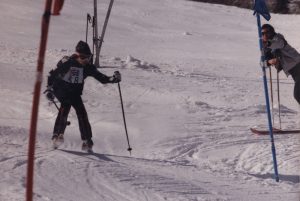 Jeune skieur passant entre deux drapeaux de course sur une piste de ski.