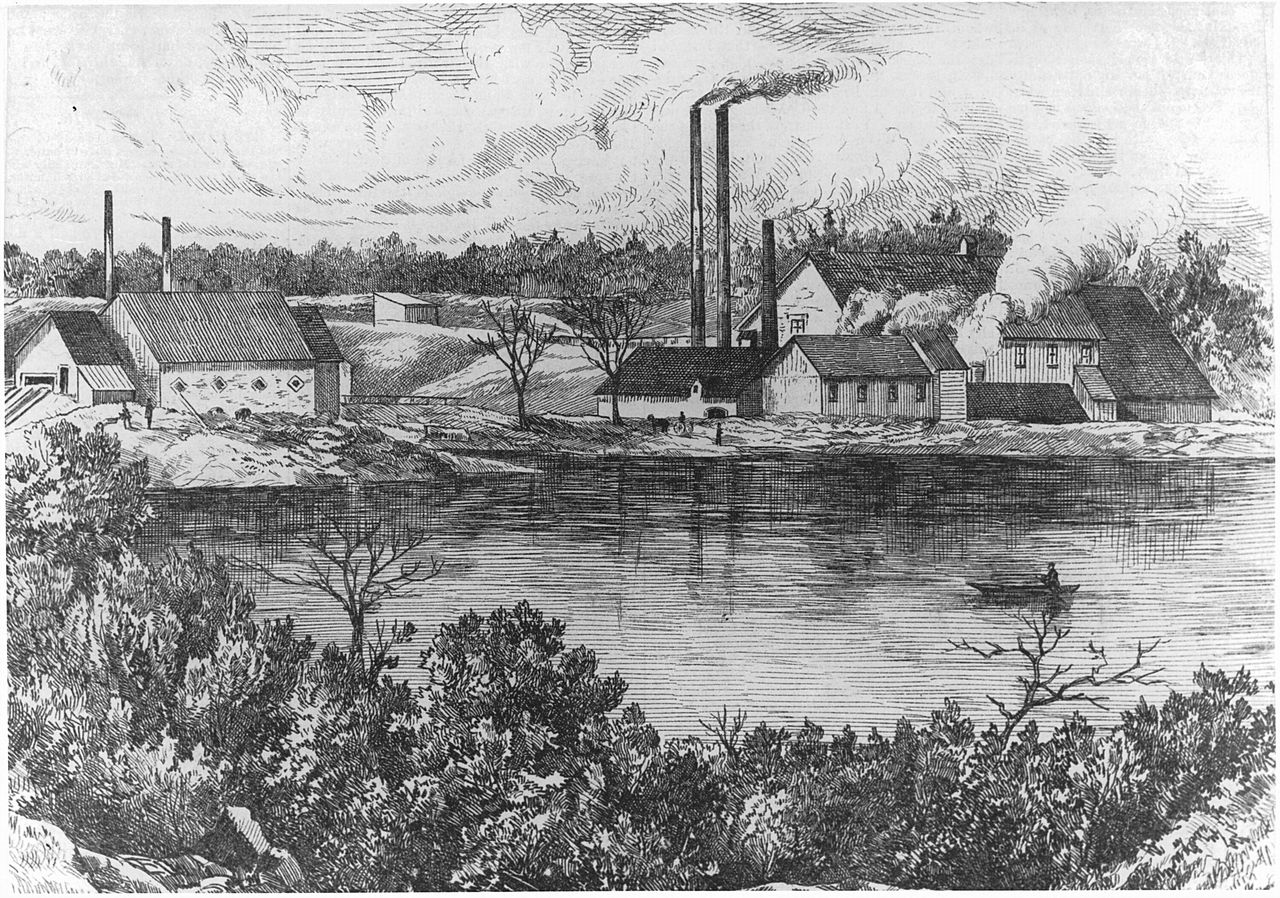 Gravure représentant la tannerie Simpson longeant la rivière Saint-François. Celle-ci comprend plusieurs bâtiments et cheminées qui émettent de la fumée.