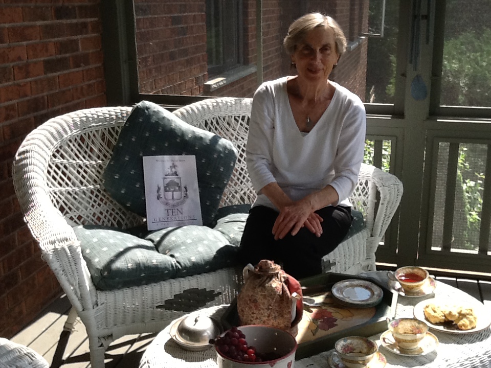 Colour photograph of a woman sitting on a bench, having tea on a porch.