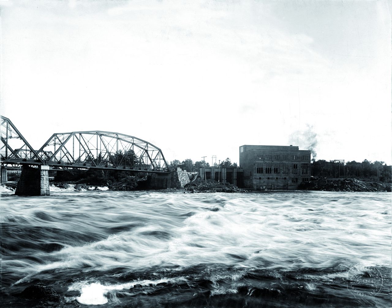 Black and white photograph of the Drummondville hydroelectric power plant and the two bridges crossing the Saint Francis River.