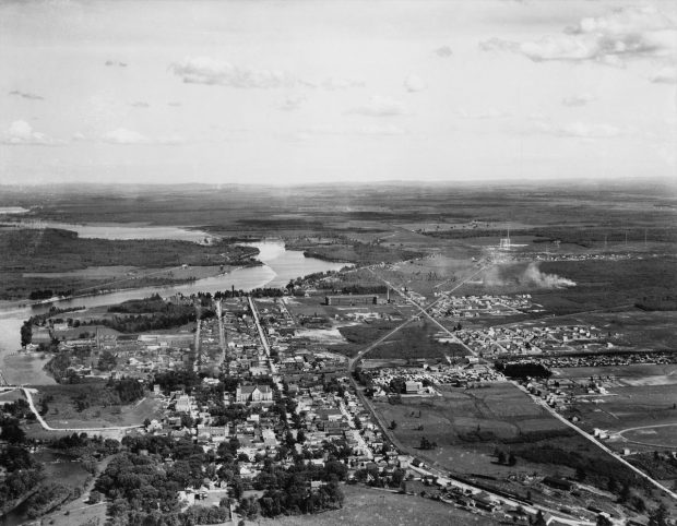 Black and white photograph showing an aerial view of downtown Drummondville. It shows houses, churches, factories, roads, and railways.