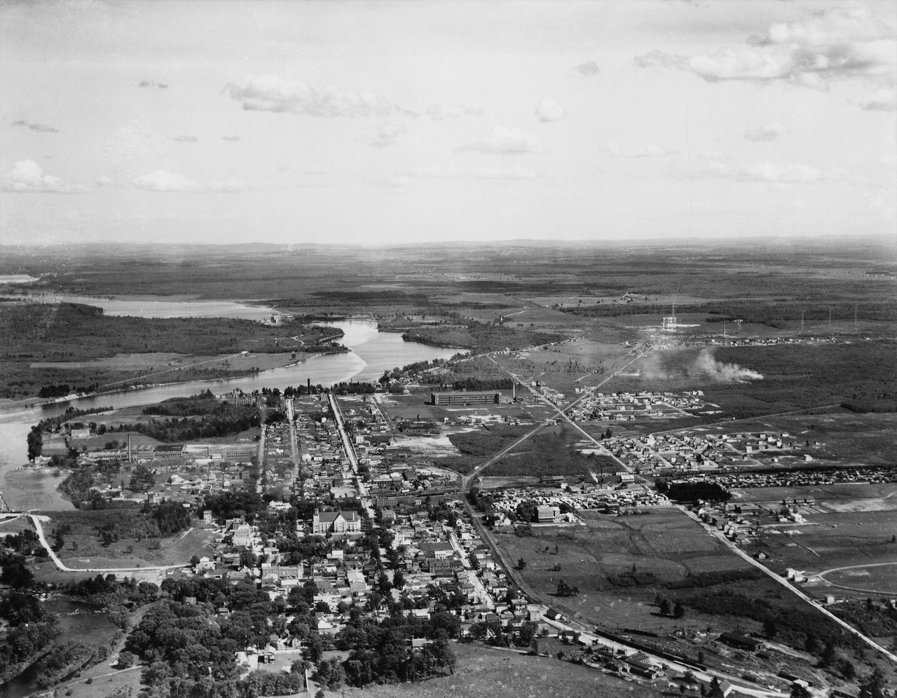 Black and white photograph showing an aerial view of downtown Drummondville. It shows houses, churches, factories, roads, and railways.