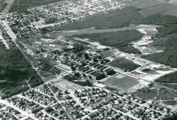 Black and white photograph showing an aerial view of the Canadian Celanese factory. It shows the various buildings of the factory, sports fields, and the surrounding workers’ areas.