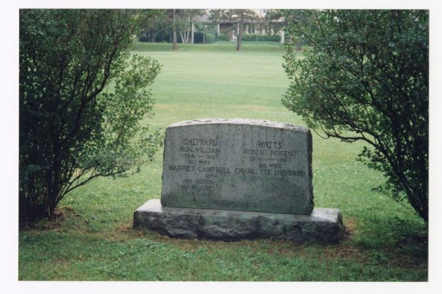 Colour photograph of a rectangular tombstone between two shrubs. Five names are inscribed on it, including Robert Nugent Watts, Charlotte Sheppard, William Sheppard, and Harriet Campbell.