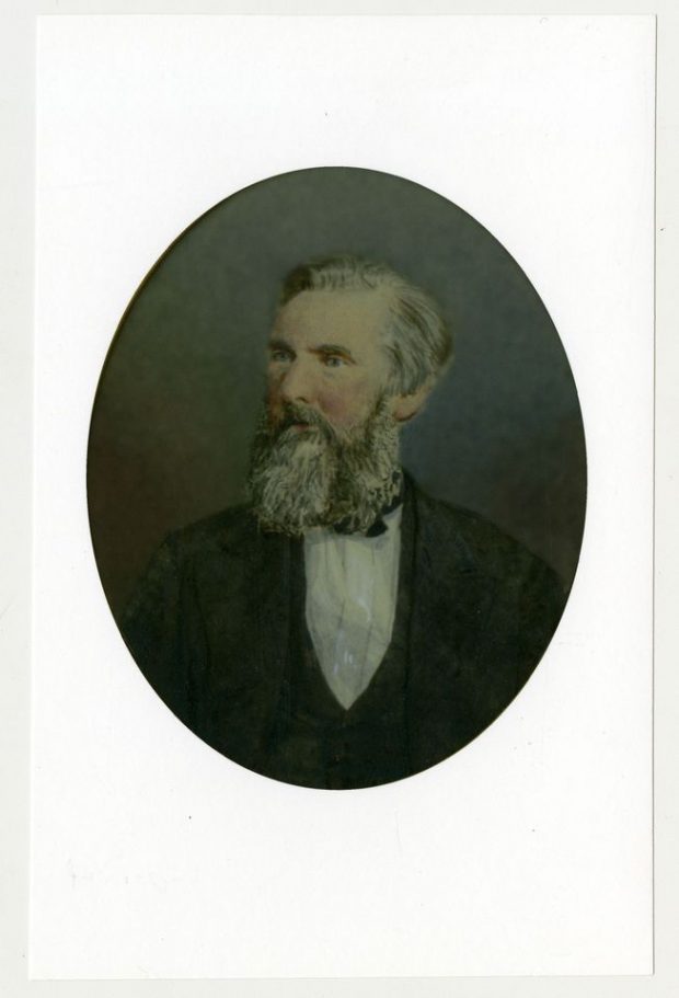 Colour portrait of a man with greying beard wearing a suit.