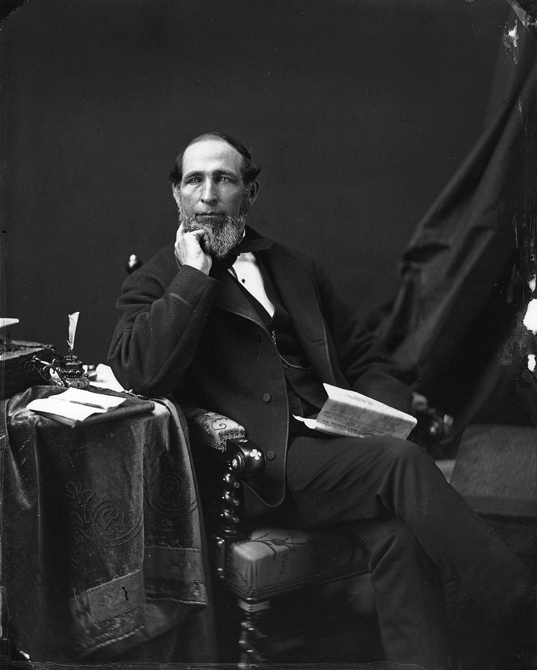 Black and white photograph of a man sitting in a chair and holding a newspaper.