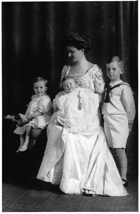 Black and white photograph of a seated woman posing with her three young children, the baby on her lap.