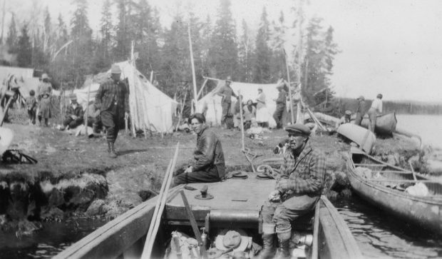 Several men, women and children are busy in a rudimentary camp set up on the banks of a river.