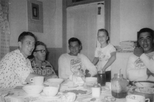 Several people are gathered around a table: two white men, two Indigenous men and a young white boy.
