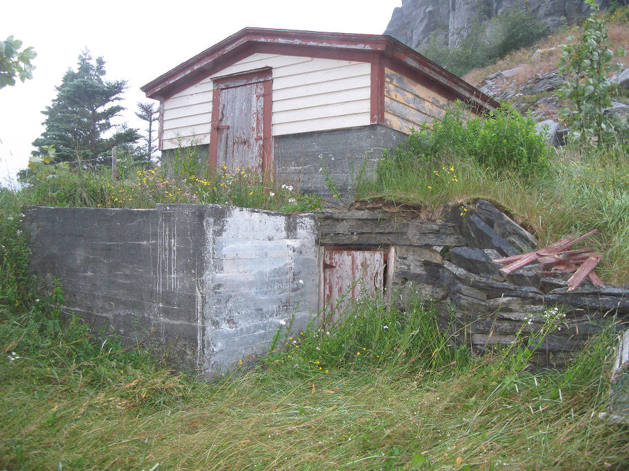 Root cellar with two entrances. The stop shed is white with a red door and roof.