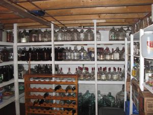 The interior of a walk-in cool room lined with shelves stocked with bottles.